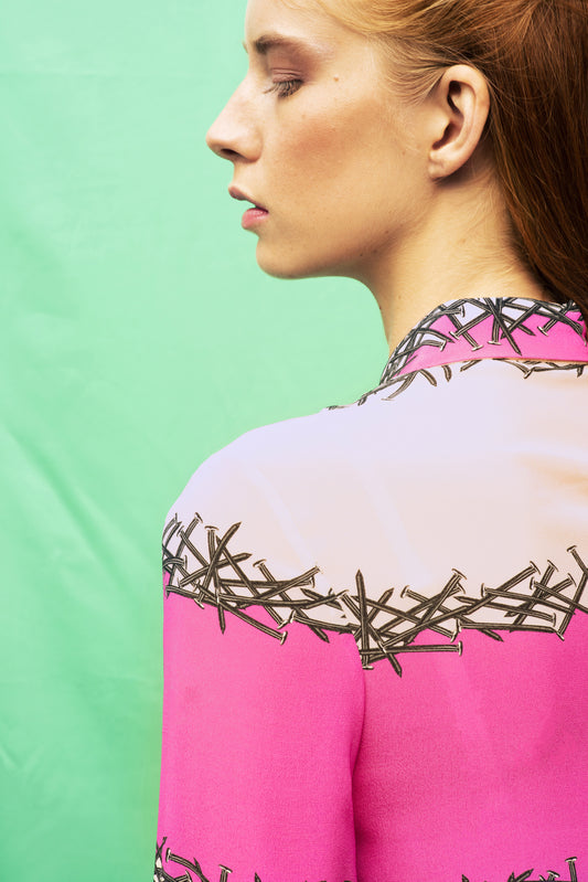 Detail of Luana Ga' printed shirt in lines of nails with a shocking pink colour block 